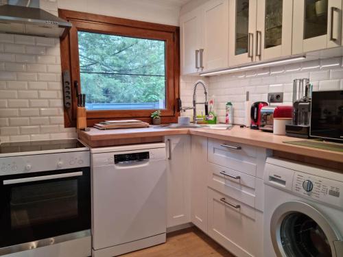 a white kitchen with a dishwasher and a window at Le Cha'let Resteigne in Wellin