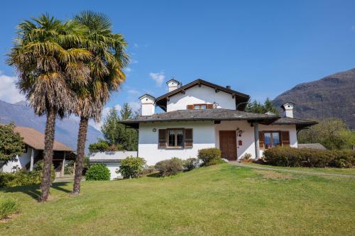 a white house with a palm tree in the yard at Villa Palma in Colico