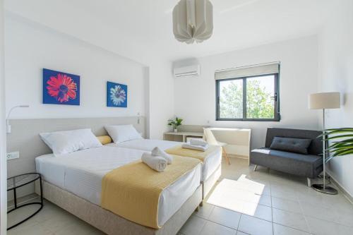 a white bedroom with a large bed and a chair at Crystal Waves lux villa-Homeleader in Chania Town