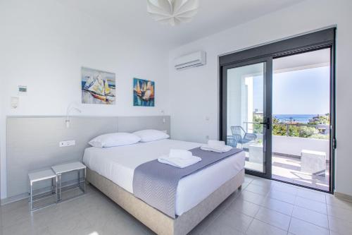 a white bedroom with a bed and a large window at Crystal Waves lux villa-Homeleader in Chania Town
