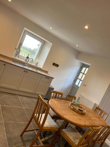 uma cozinha com uma mesa e cadeiras de madeira e um lavatório em Tosside Fold Farm Cottage em Skipton