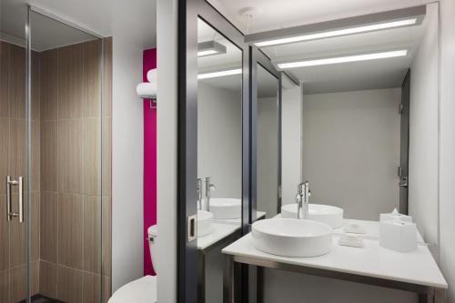 a bathroom with two sinks and a toilet and a mirror at Aloft Atlanta Downtown in Atlanta