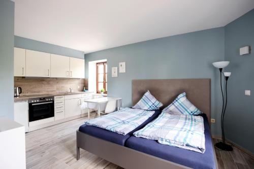 a bedroom with a bed with blue walls and a kitchen at A Mëchels in Bettel