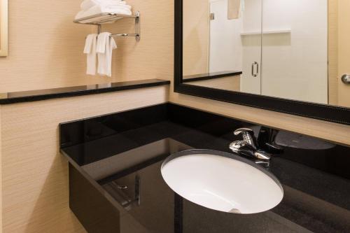 W łazience znajduje się umywalka i lustro. w obiekcie Fairfield Inn & Suites by Marriott Utica w mieście Utica