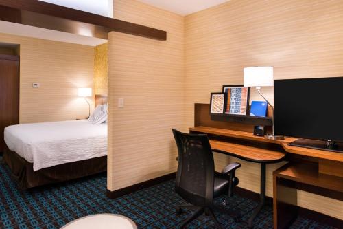 a hotel room with a desk with a computer and a bed at Fairfield Inn & Suites by Marriott Utica in Utica