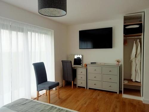 a bedroom with two chairs and a desk with a television at Flotnar Hús - Ensuite Rooms in Keiss