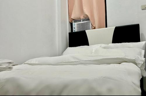 1 Schlafzimmer mit 2 weißen Betten und einem Fenster in der Unterkunft Private room with AC and fan at EKG House Rental in Manila