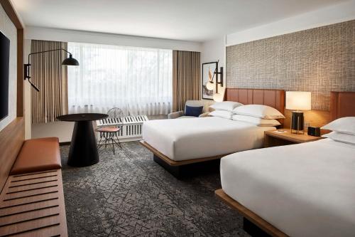 una camera d'albergo con due letti e un tavolo di Sheraton Reston a Reston