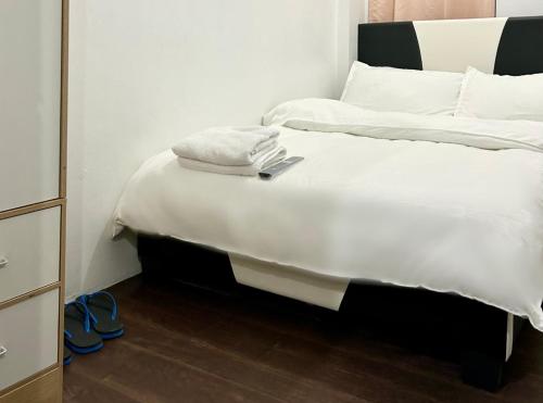 ein Bett mit weißer Bettwäsche und Handtüchern darüber in der Unterkunft Private room with AC and fan at EKG House Rental in Manila