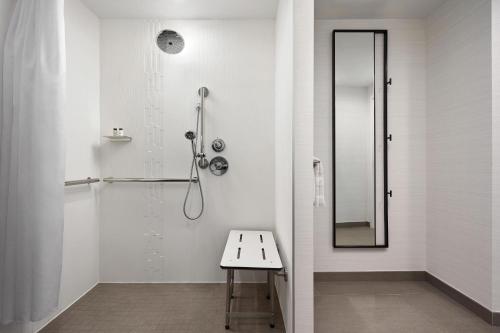 a white bathroom with a shower and a bench at Sheraton Reston in Reston