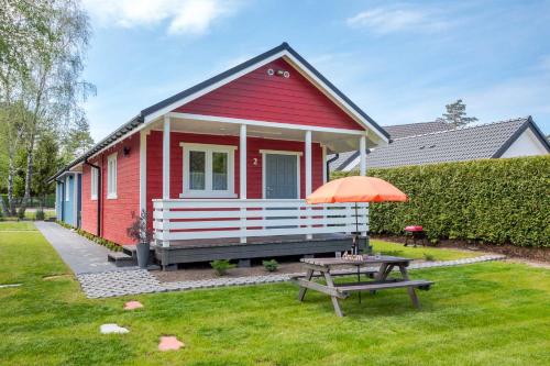 a red house with a picnic table and an orange umbrella at Domki Bruno Mare in Bobolin