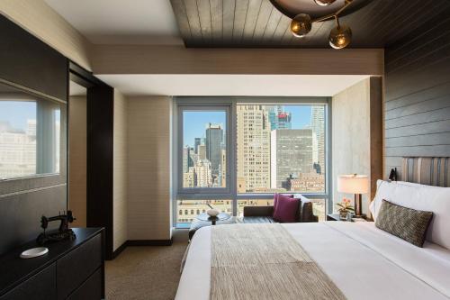 ニューヨークにあるルネッサンス ニューヨーク ミッドタウン ホテル ア マリオット ラグジュアリー＆ライフスタイル ホテルの大きなベッドと大きな窓が備わるホテルルームです。