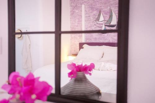 a window with a vase with flowers in front of a bed at Apsenti couples only in Agios Ioannis Mykonos