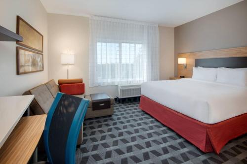 TownePlace Suites by Marriott Niceville Eglin AFB Area في نايسفيل: غرفة فندقية بسرير كبير وكرسي