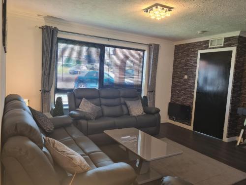 a living room with a couch and a table at 3 BEDROOM HOUSE WITH FREE PARKING - Travel Host in Nitshill
