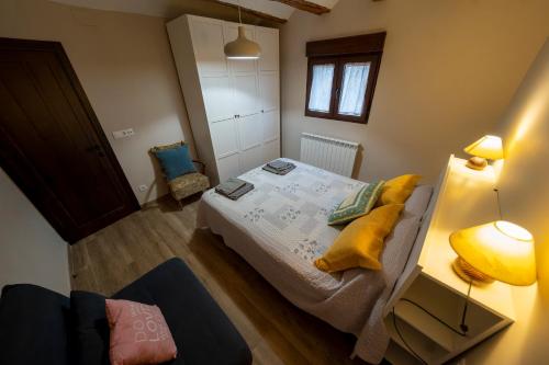 a small bedroom with a bed with yellow pillows at Casa Rural Casa Clemen in Villalba Baja