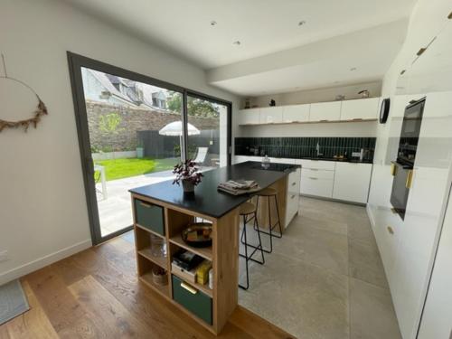 une grande cuisine avec un îlot et une grande fenêtre dans l'établissement Vannes centre à pied grande villa familiale, à Vannes