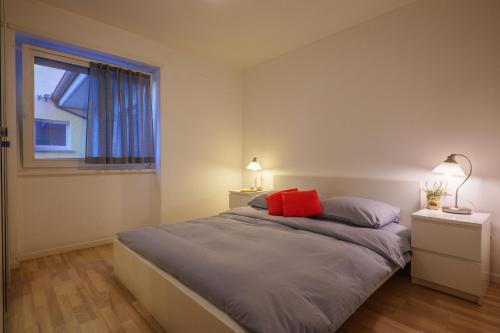 Schlafzimmer mit einem Bett mit roten Kissen und einem Fenster in der Unterkunft Residence Girasole Casa Rossa A in Colico