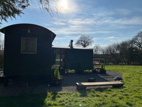 a black shed with a bench in front of it at Shepherds Hut in enclosed field in Cardiff
