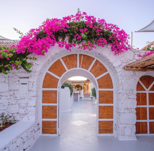 une arche avec des fleurs roses sur un mur dans l'établissement Apsenti couples only, à Agios Ioannis Mykonos