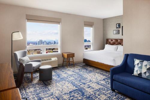 um quarto de hotel com uma cama e uma cadeira e uma janela em Four Points by Sheraton Calgary Airport em Calgary