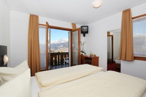 a bedroom with a bed and a view of a mountain at Hotel Central in Obersaxen