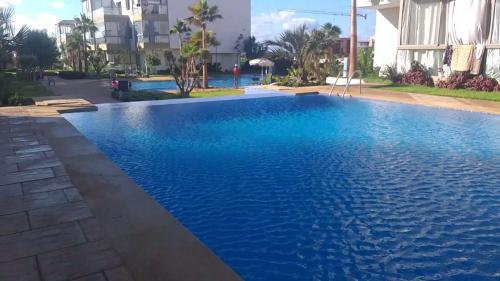 a swimming pool in a resort with blue water at Sidi Rahal Blue Beach Appartement Pieds Dans L'eau in Sidi Rahal