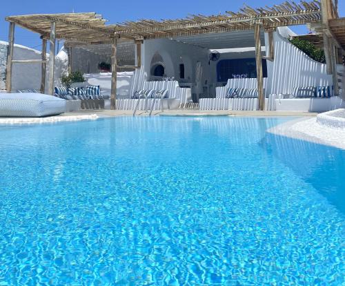 a swimming pool with blue water and white chairs at Apsenti couples only in Agios Ioannis Mykonos