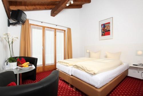 a bedroom with a bed and a table and a chair at Hotel Central in Obersaxen