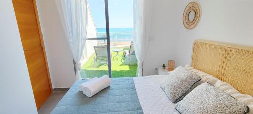 a bedroom with a bed with a view of the ocean at Apartamento Jardines de Deveses by DENIA COSTA in Denia