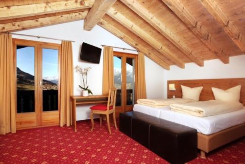 1 dormitorio con 1 cama, escritorio y ventanas en Hotel Central en Obersaxen