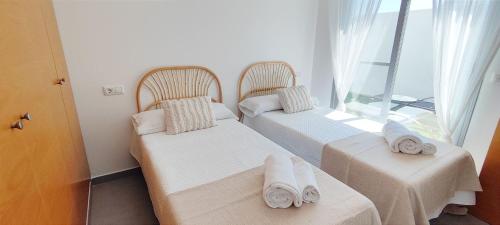 two beds in a room with a window at Apartamento Jardines de Deveses by DENIA COSTA in Denia
