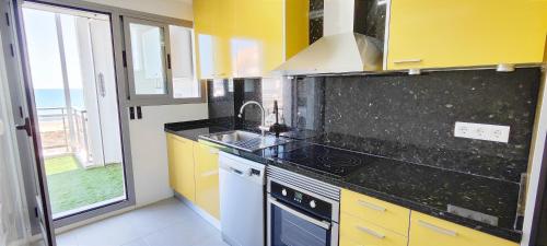 a kitchen with yellow and black counters and a sink at Apartamento Jardines de Deveses by DENIA COSTA in Denia