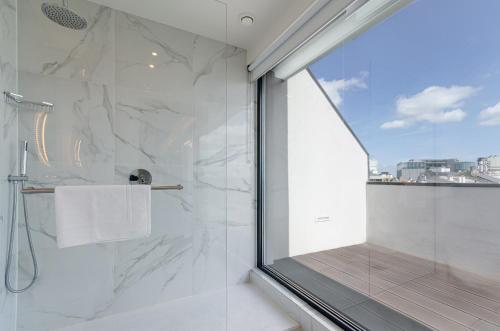 uma casa de banho com um chuveiro e uma janela de vidro em OMID Saldanha Hotel em Lisboa