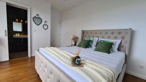 una camera da letto con un grande letto bianco con cuscini verdi di Magnolia Residence - In the Center of the Island a Ribeira Grande