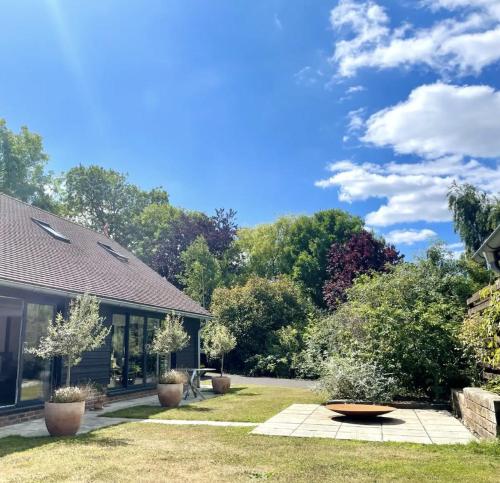 a yard with a house and trees in the background at The Barn in Chichester