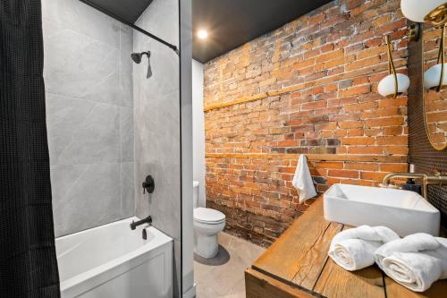 a bathroom with a white sink and a brick wall at The Goodman: Front Street Flats in Belleville