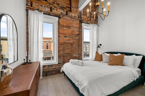 a bedroom with a bed and a brick wall at The Goodman: Front Street Flats in Belleville