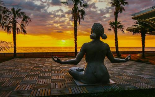 a statue of a woman sitting in a yoga pose on the beach at Dreamland Oasis apartment Chakvi in Chakvi