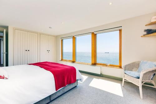 a bedroom with a bed and two windows at Dolphins in Coverack