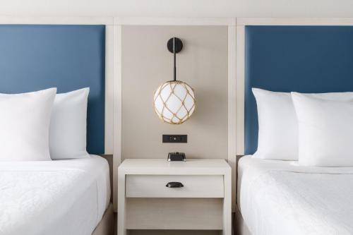 a bedroom with two beds and a nightstand between them at Hilton Garden Inn Ocean City Oceanfront in Ocean City