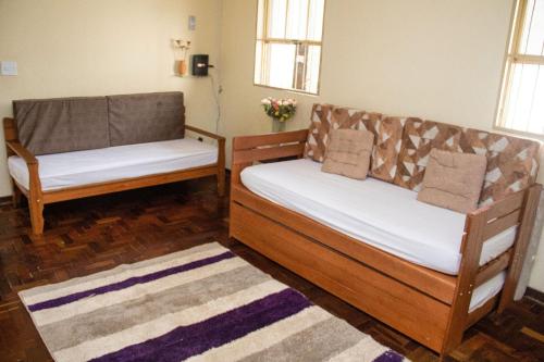 two wooden beds in a room with a rug at Casa espaçosa e confortável na região da Pampulha in Belo Horizonte