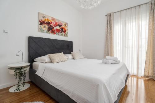 Apartments Dante في بودسترانا: غرفة نوم بسرير كبير مع شراشف بيضاء