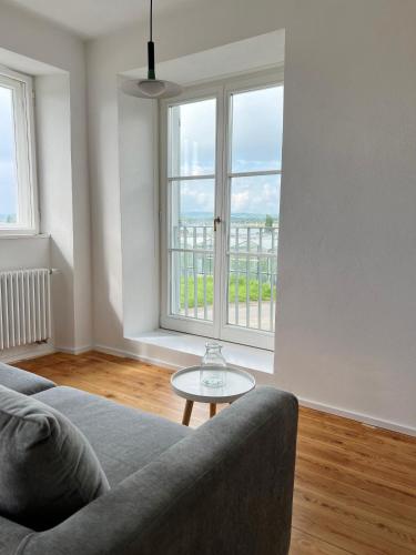 a living room with a couch and a table and windows at Haus Münsterblick in Reichenau