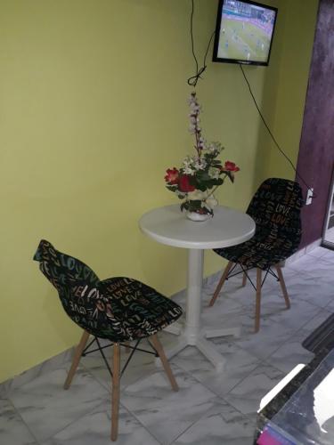 two chairs and a table with a vase of flowers at Loft Amazônia in Belém