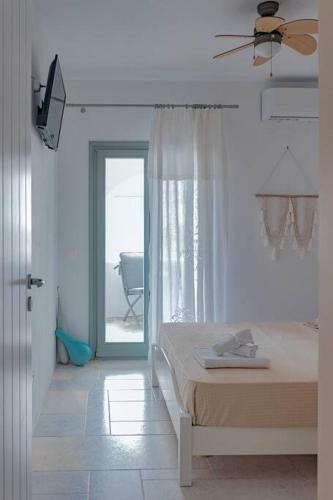 a white bedroom with a bed and a sliding glass door at Martha's filoxenia in Drios