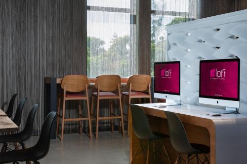a room with chairs and a desk with a computer on it at Aloft Miami Aventura in Aventura