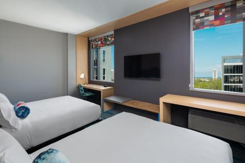 a hotel room with two beds and a flat screen tv at Aloft Miami Aventura in Aventura