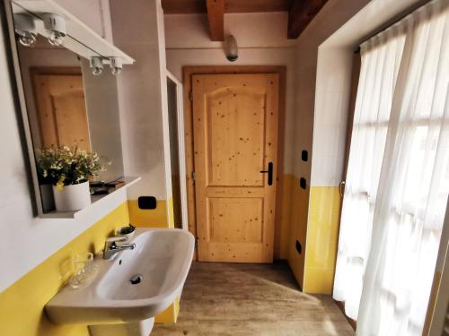 La salle de bains est pourvue d'un lavabo, d'un miroir et d'une porte. dans l'établissement B&B Blumenstube, à Sant’Orsola