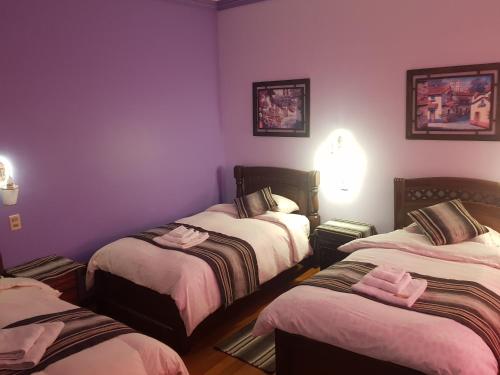 three beds in a room with purple walls at Hostal Phaxsi in Comunidad Yumani